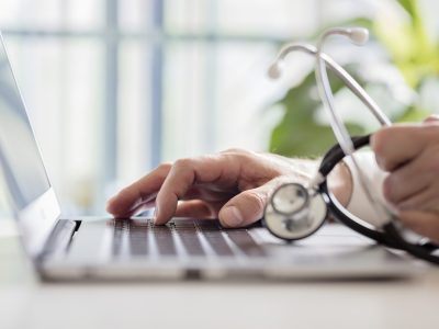 Doctor entering patient notes on a laptop in surgery